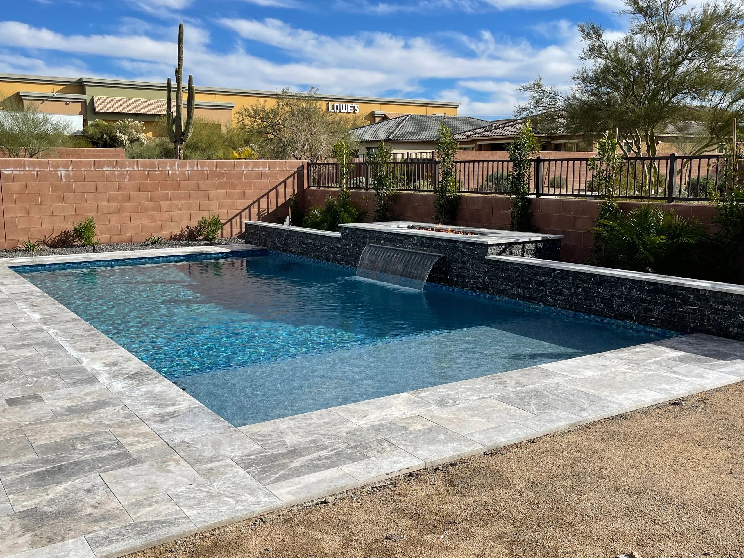 A pool with a waterfall and a stone wall.