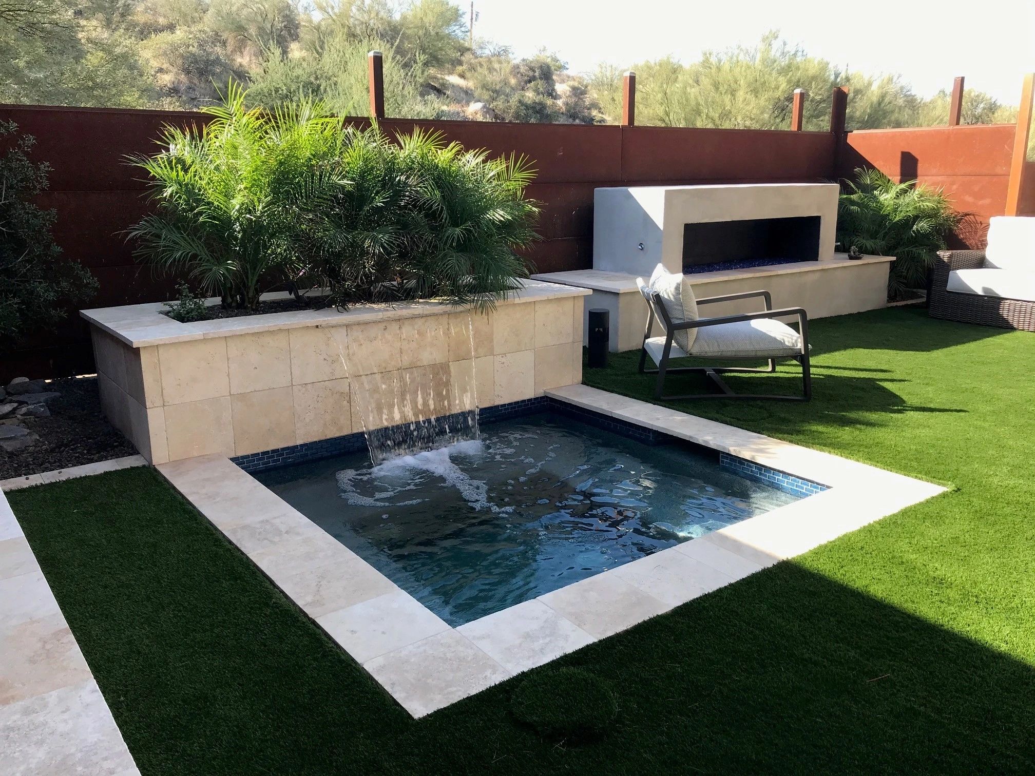 A small pool with water jets and a fire place.