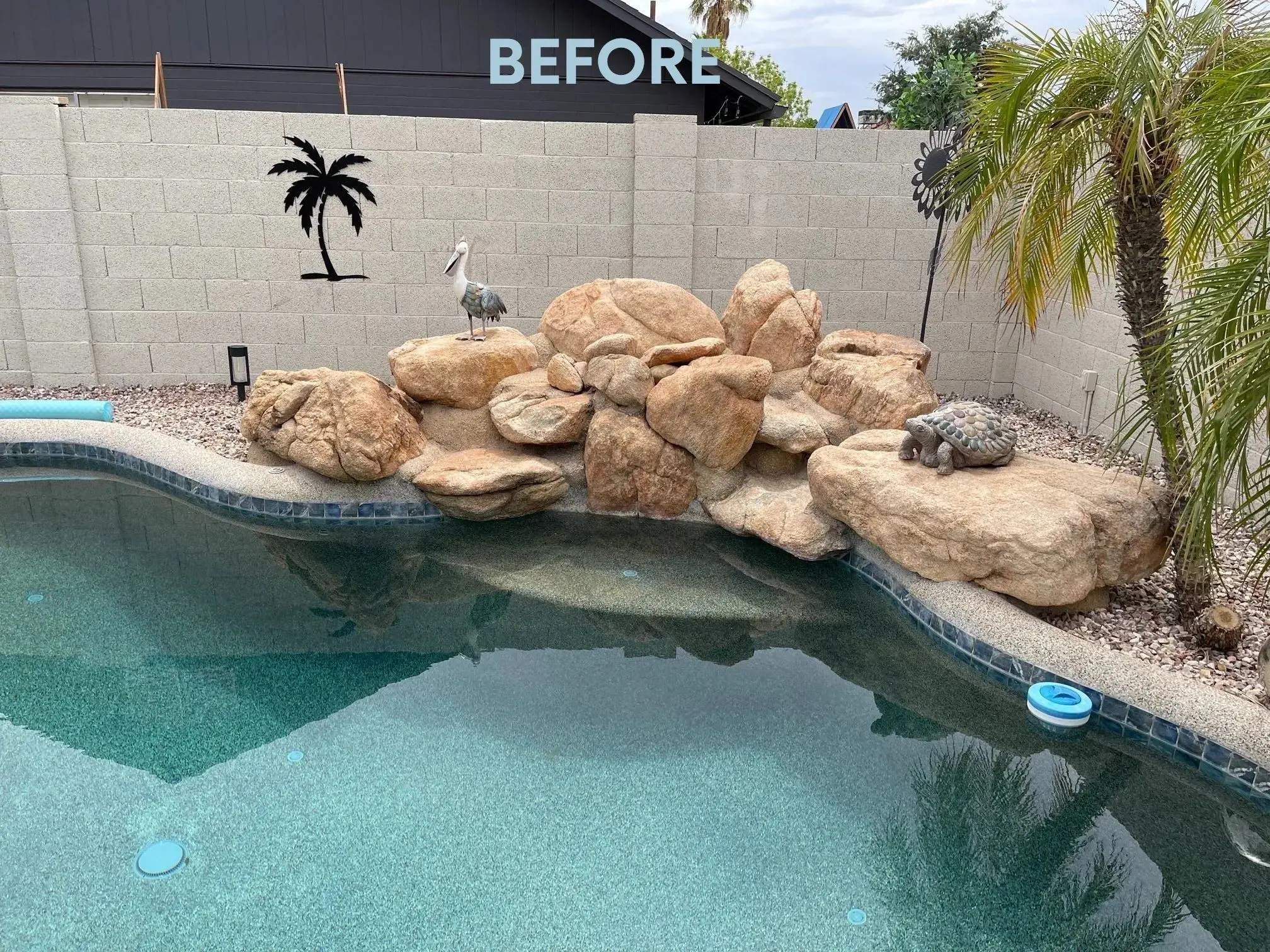 A pool with rocks and palm trees in the back.