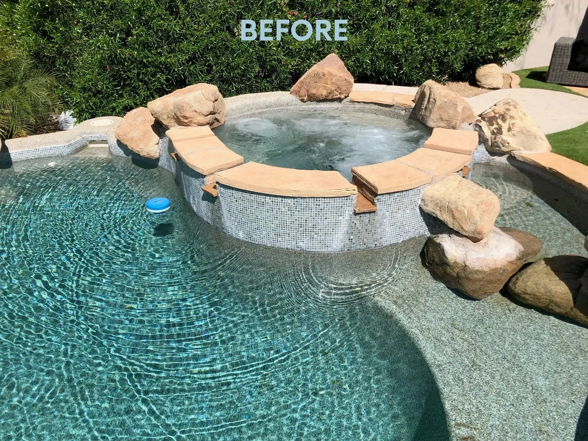 A pool with a stone surround and a rock bench.