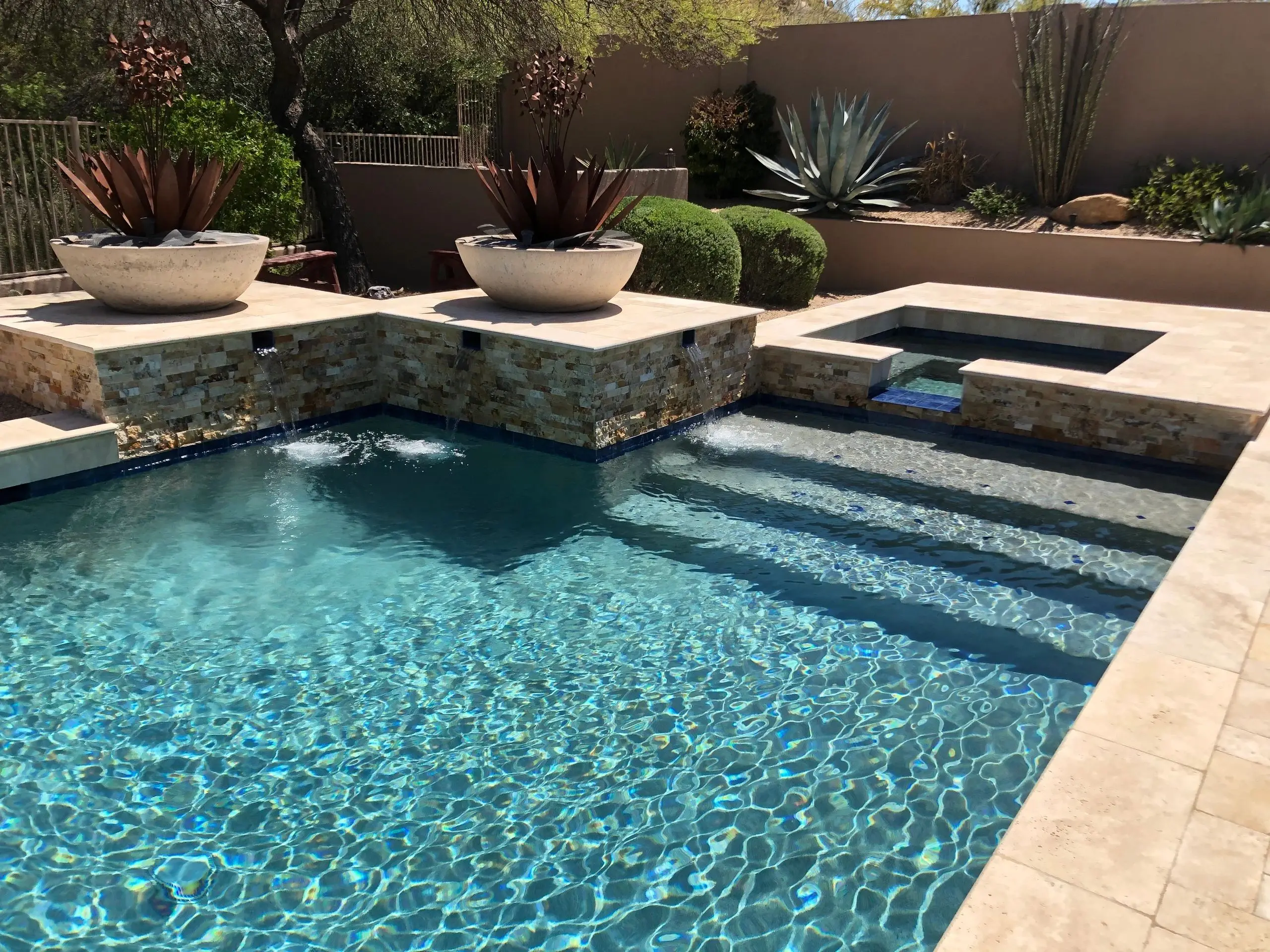 A pool with steps and plants in the middle of it.