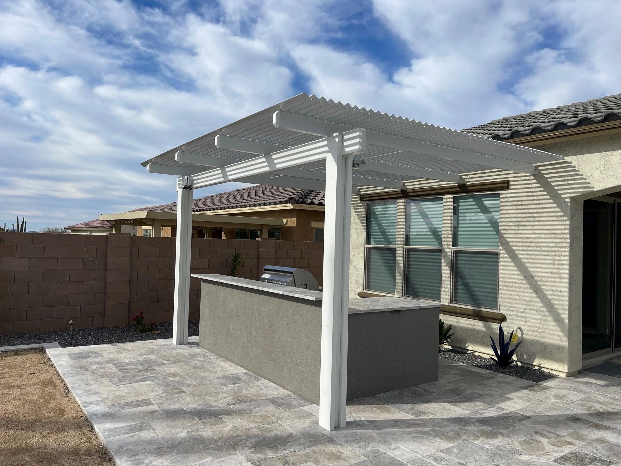 A patio with an outdoor bar and a pergola.