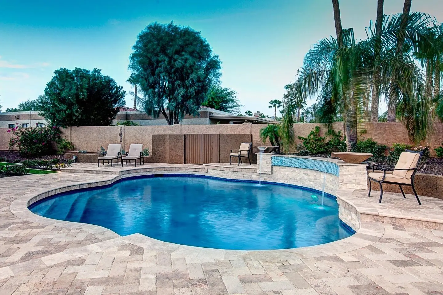 A pool with chairs and trees in the background