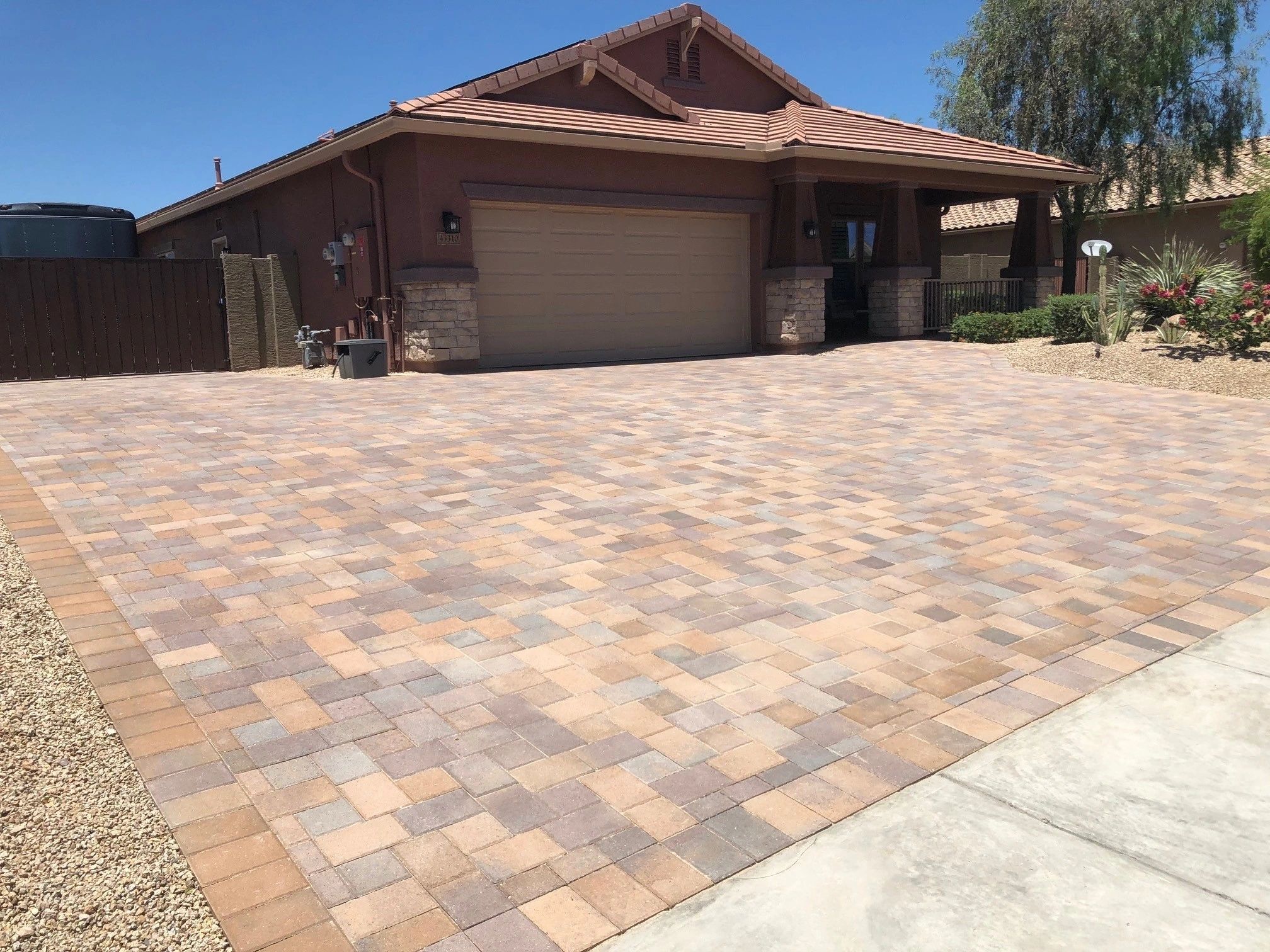 A driveway with a brick pattern and a tan roof.