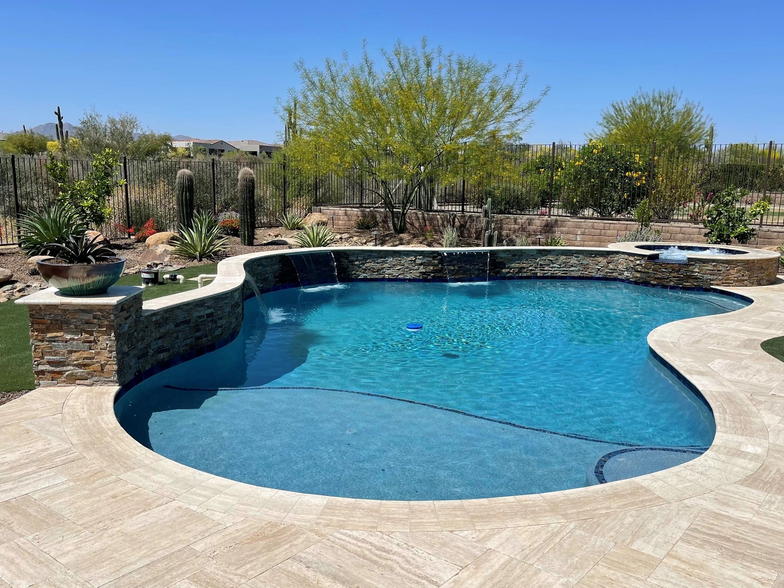 A pool with a stone wall and a water feature.