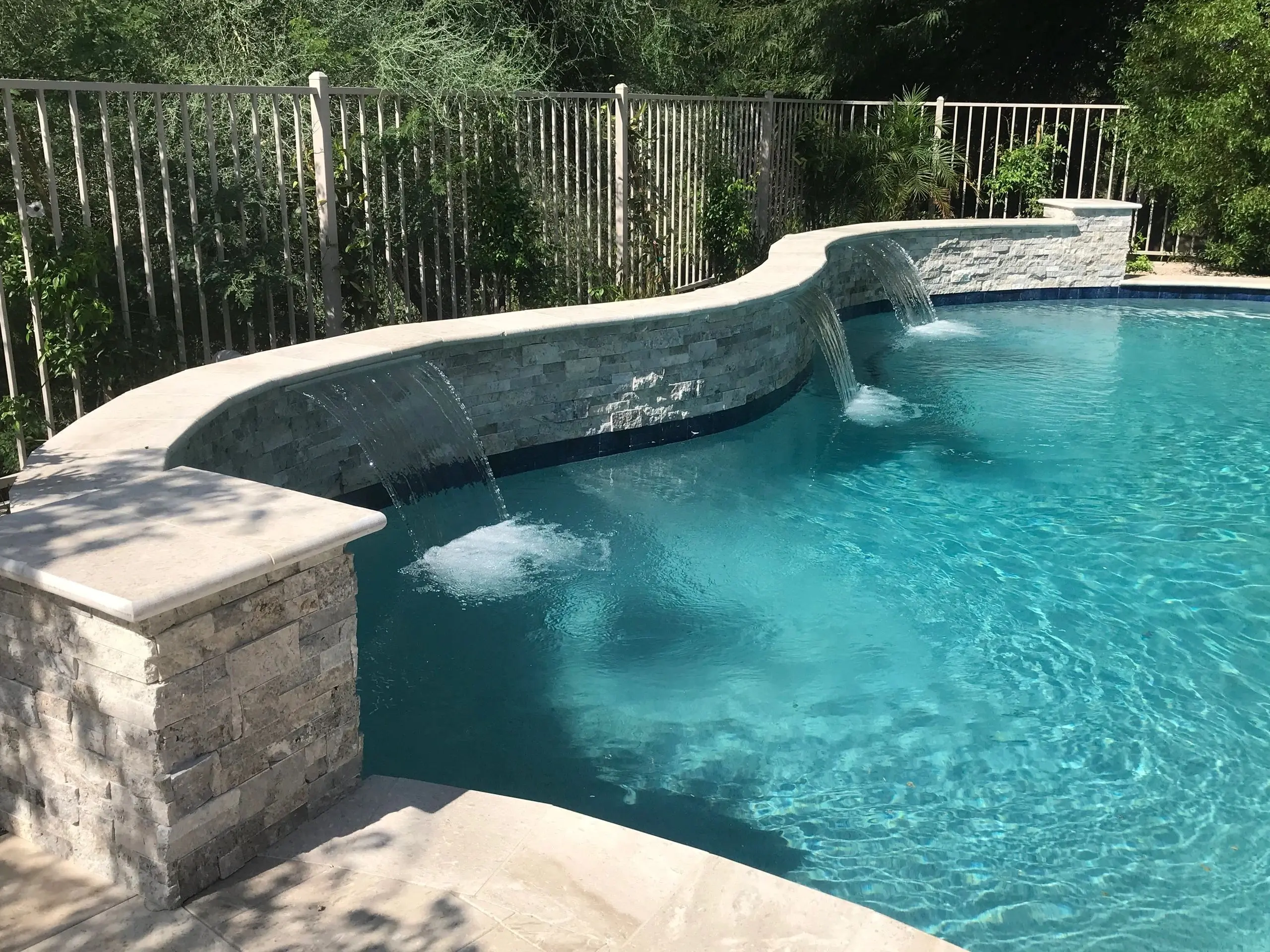 A swimming pool with water falling from the side.