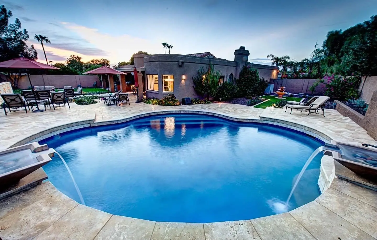 A pool with water jets and a house in the background.