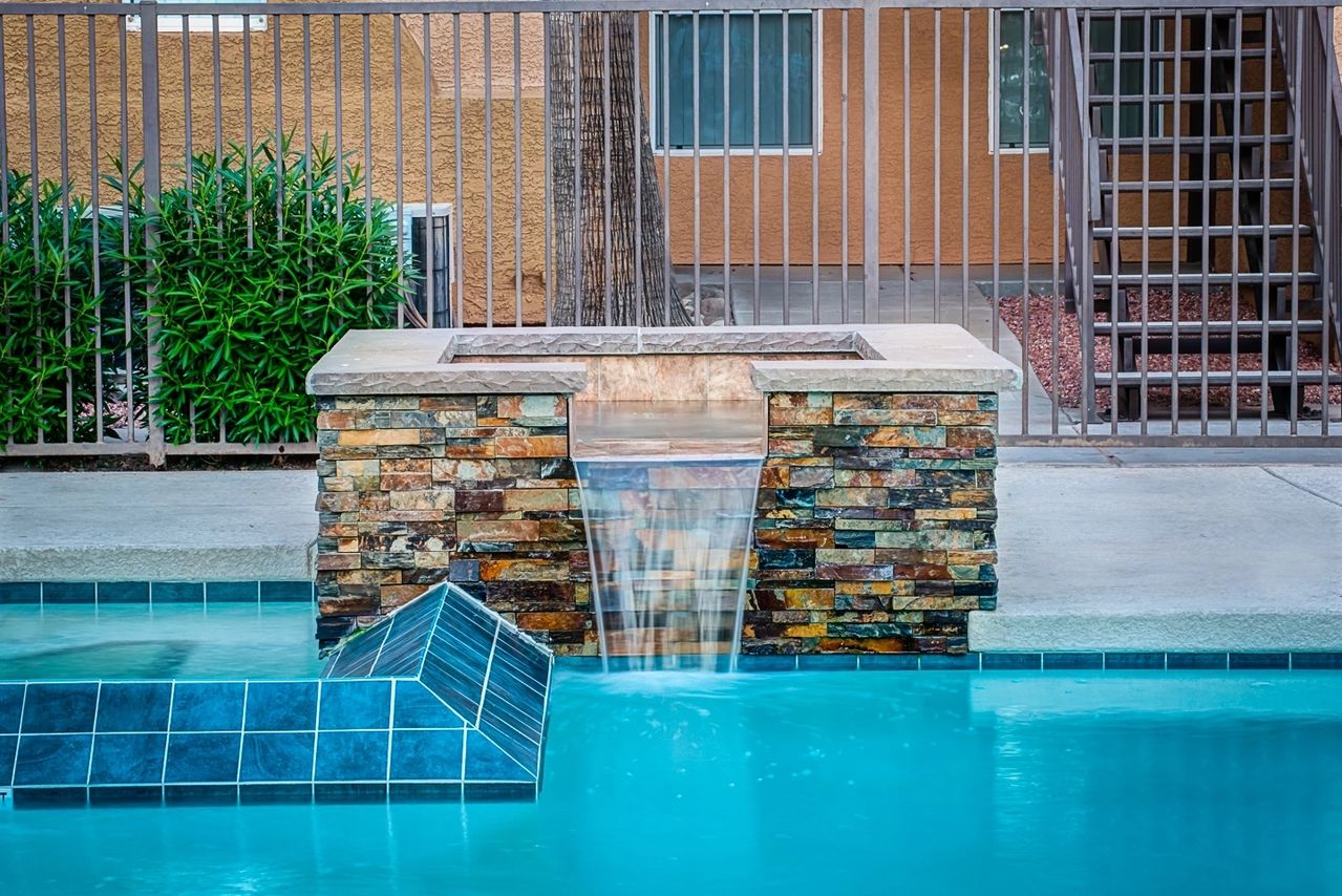 A pool with a fire pit and water feature.