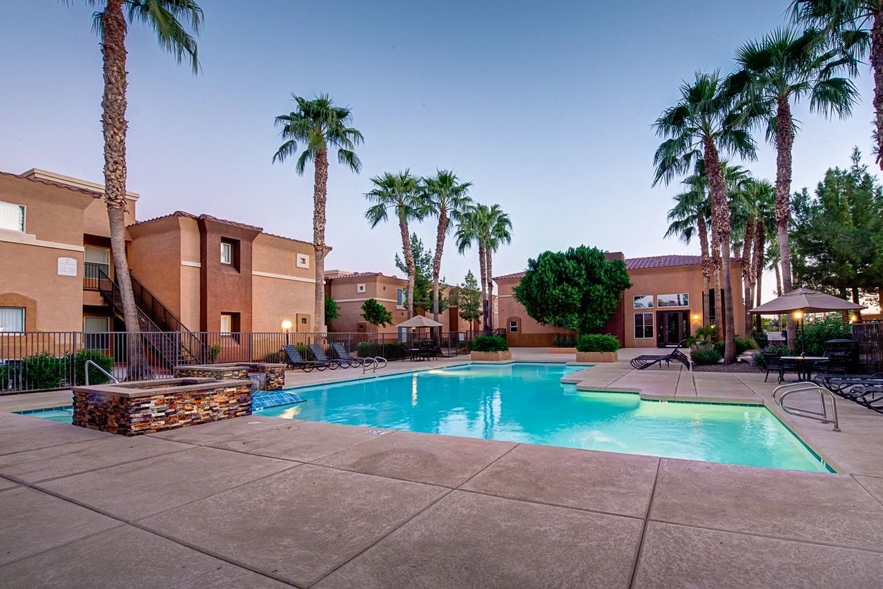 A pool with palm trees and a building in the background.